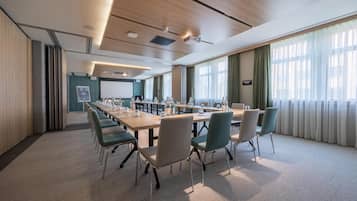 A conference room with a long table, chairs, and a projector screen.