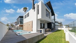Ein modernes, zweistöckiges Haus mit Swimmingpool, Gartenmöbeln und einem großen Schornstein.