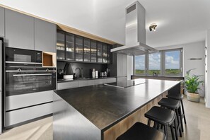 A modern kitchen with a large island, built-in appliances, and a view of the outdoors. - Ocean 9 Beachfront Residence (Cape Town)