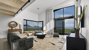 Ein modernes Wohnzimmer mit großem Fenster, einer Couch, einem Couchtisch und einem Teppich.