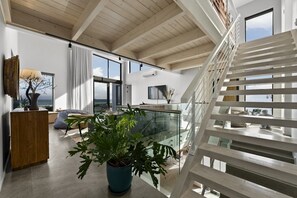 A modern interior with a staircase, a large potted plant, and a view of the ocean. - Ocean 9 Beachfront Residence (Cape Town)