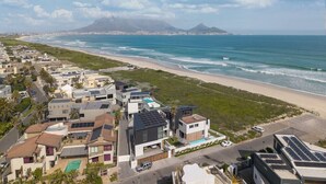 A coastal residential area with modern houses, a beach, and a mountain in the background.
