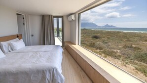 A bedroom with a large window offering a view of a coastal landscape.