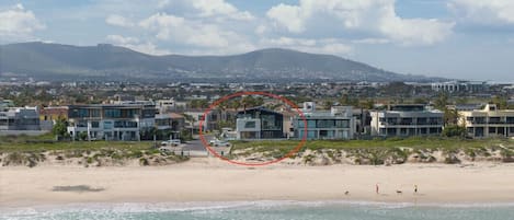 A coastal residential area with modern houses, a beach, and a mountain in the background.