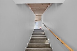 A staircase with a wooden handrail leading to a landing with a window.