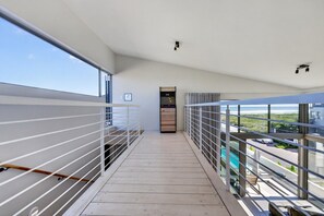 A modern balcony with a wooden floor, metal railings, and a view of the sea.