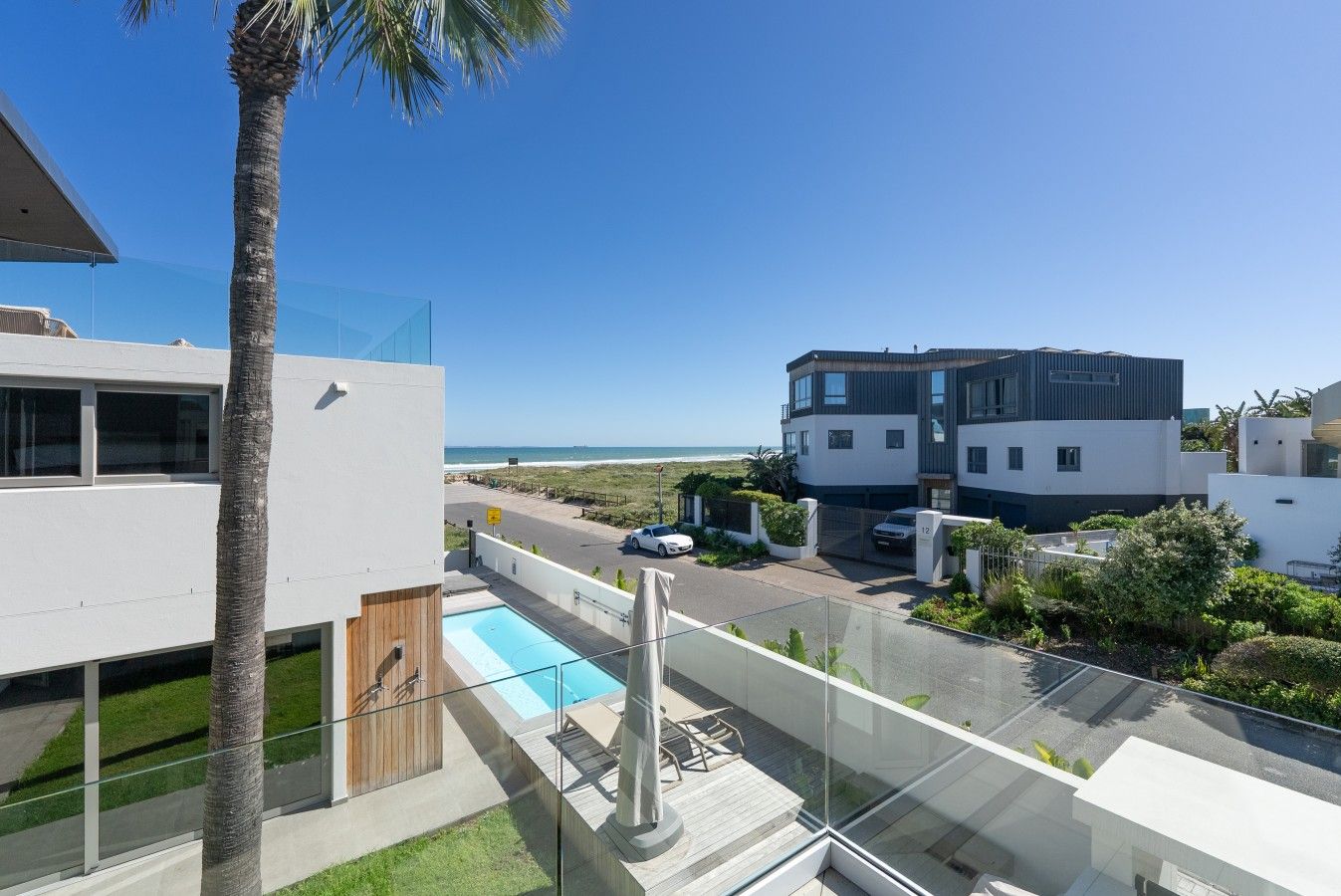 Un edificio residencial moderno con piscina, vistas despejadas al océano y un césped bien cuidado.