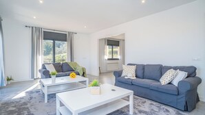 A modern living room with a grey sofa, a white coffee table, and a grey carpet. - Jouvacations Villa Rodil (Figueres)