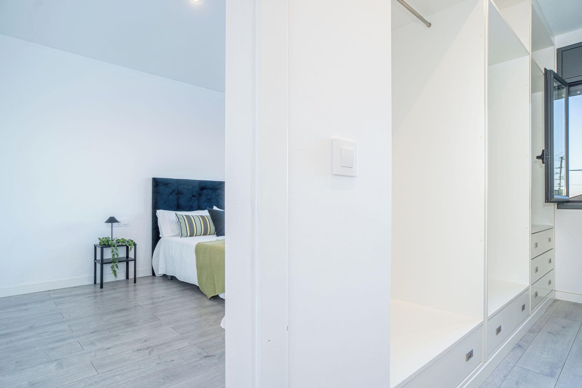 A bedroom with a bed, bedside table, and a window.
