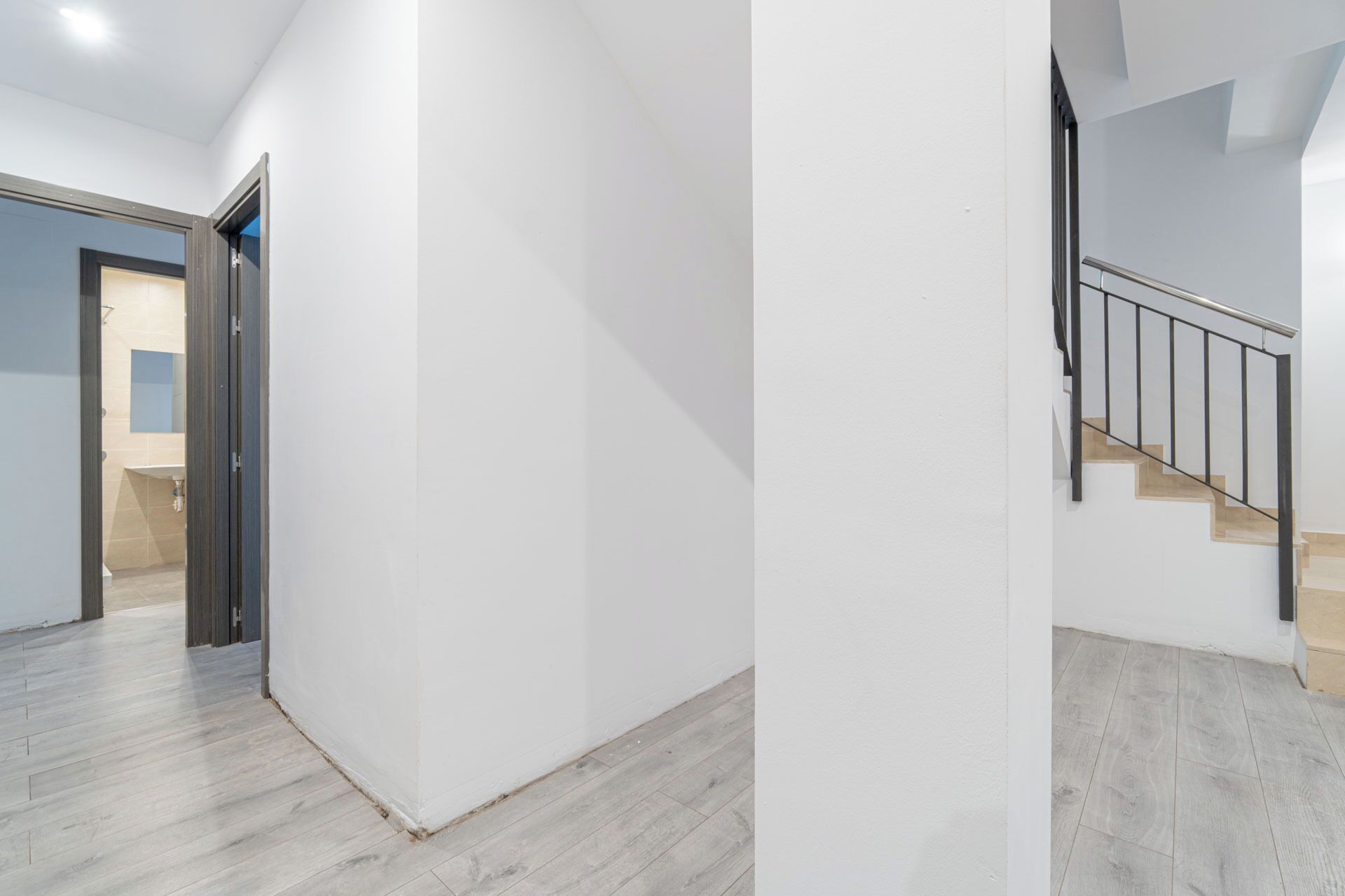 A modern interior with a staircase, a hallway, and a bathroom visible through an open door.