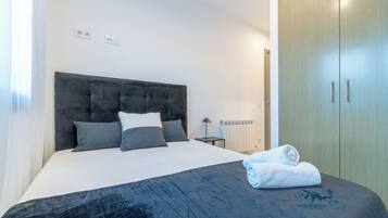 A bedroom with a bed, a nightstand, a radiator, and a wardrobe.