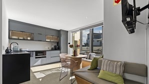A modern kitchen with a dining area, a sofa, and a large window. - Ocean 9 - Pool-Suite (Cape Town)