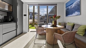 A modern kitchen with a dining area, a large window, and a view of the outside. - Ocean 9 - Pool-Suite (Cape Town)