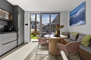 A modern kitchen with a dining area, a large window, and a view of the outside. - Ocean 9 - Pool-Suite (Cape Town)