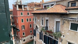 Un canal étroit où circule une gondole, bordé de bâtiments historiques dotés de balcons et de fenêtres.