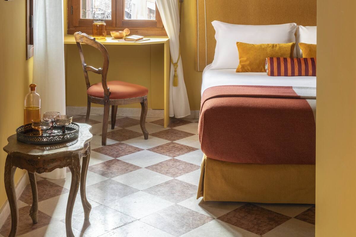 A room with a bed, a desk, a chair, and a table.