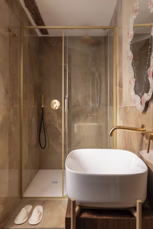 A bathroom with a glass-enclosed shower, a freestanding bathtub, and a mirror with a decorative frame. - Hotel Riva (Venice)