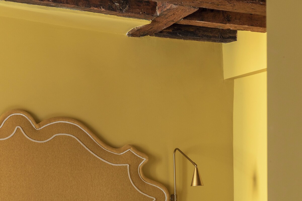 Un lit avec une tête de lit en bois, une table de chevet avec une lampe et une petite table de nuit avec une tasse.