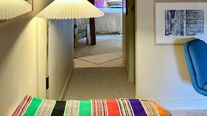 A hallway with a lamp, a bed in the background, and framed pictures on the wall. - Guest Room Sable - Auberge Radieuse (Azay-le-Rideau)