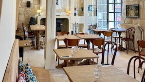 A cozy restaurant with wooden tables and benches, stone walls, and large windows. - Guest room Jaune - Auberge Radieuse (Azay-le-Rideau)