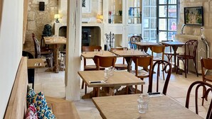 Un restaurant chaleureux avec des tables et des bancs en bois, des murs en pierre et de grandes fenêtres.