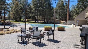Eine Terrasse mit Sitzgelegenheit im Freien, einem Pool und Blick auf Bäume sowie ein Gebäude im Hintergrund.