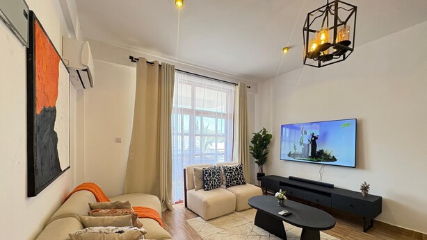 A modern living room with a sofa set, a coffee table, a TV, and a decorative light fixture.