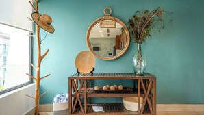 A wooden console table with a mirror, a hat rack, and a vase with dried flowers.