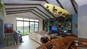 A spacious living room with a large window, a wooden dining table, and a cozy seating area.