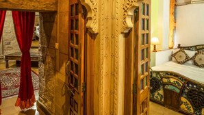 An ornate room with a bed, a red curtain, and a patterned headboard. - Hotel Rajmandir  (Jaisalmer)