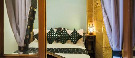 A bed with a white and green polka dot bedspread, a wooden headboard, and a small bedside table with a lamp.