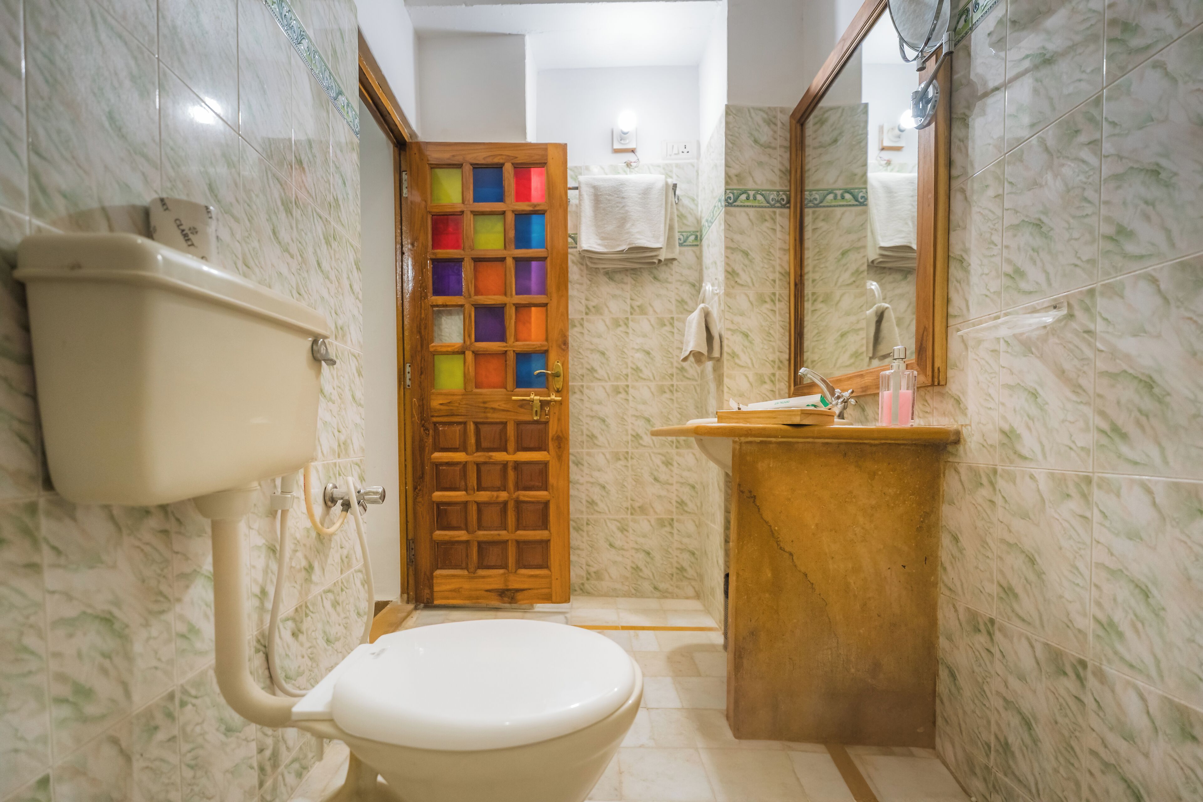 A bathroom with a toilet, sink, and a mirror.