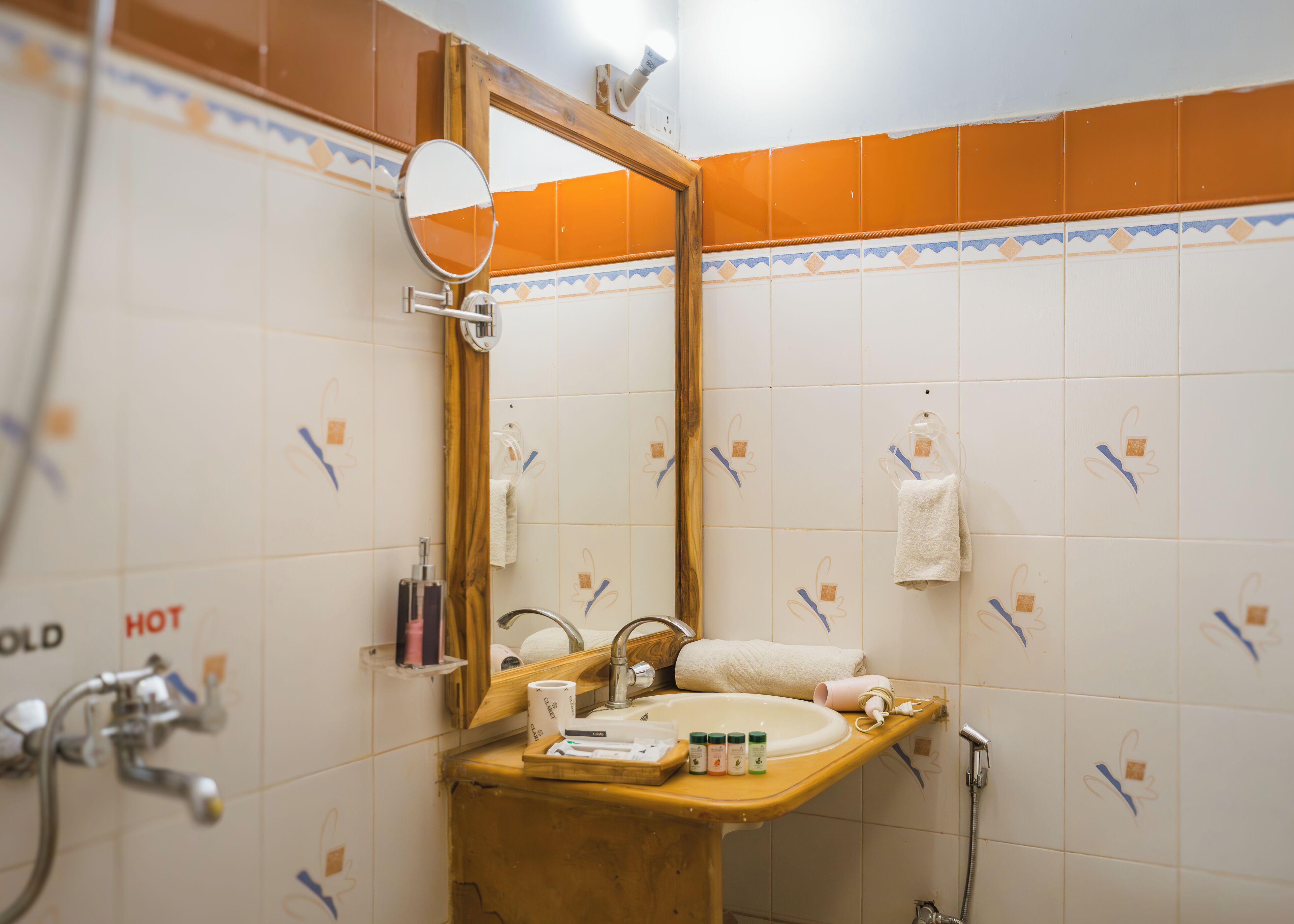 Un baño con un lavamanos de madera, un espejo, un perchero para toallas y una ducha.