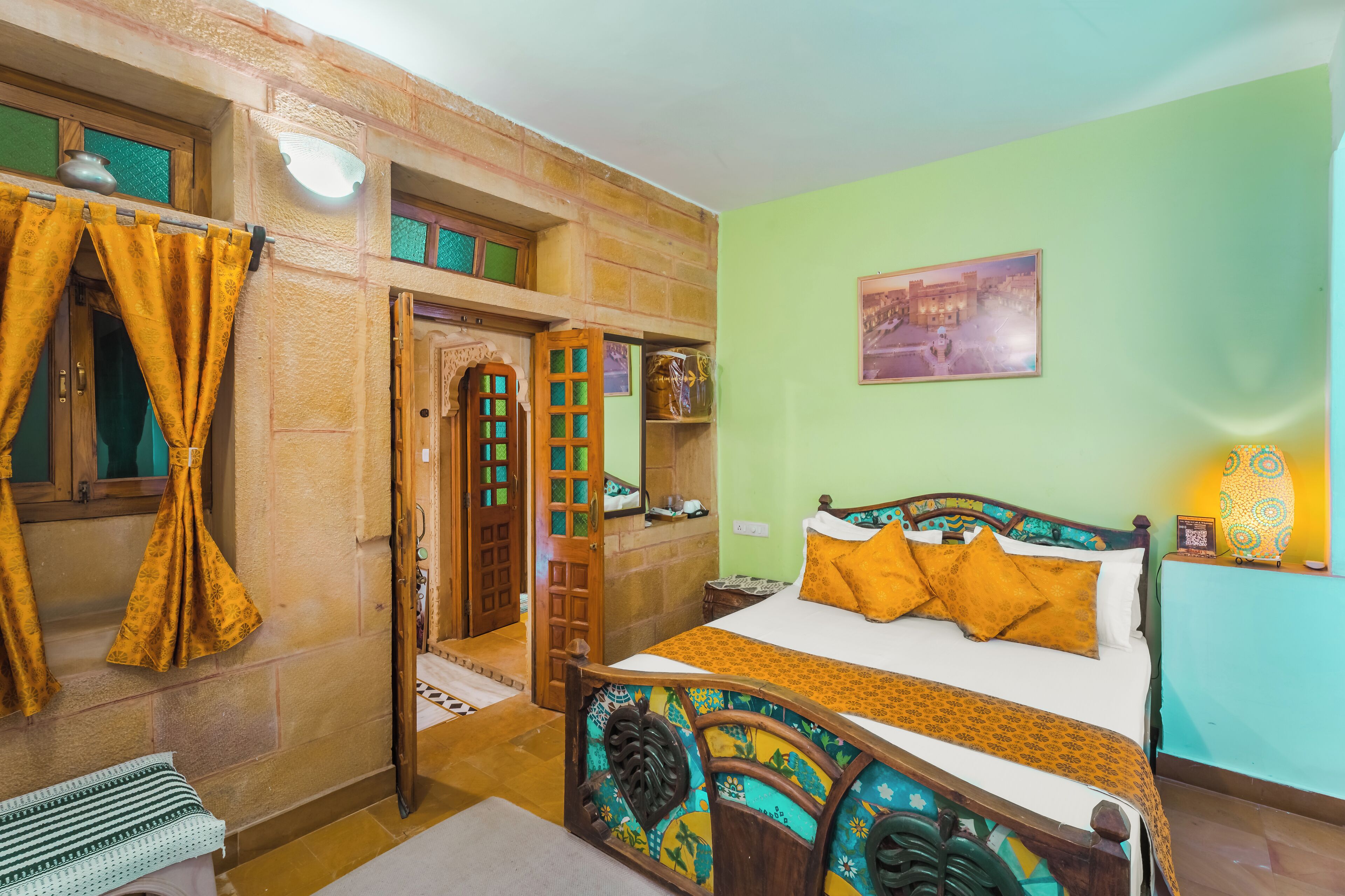 A room with a bed, a wooden door, a green wall, and a painting.