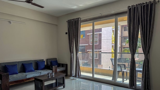 A living room with a sofa, a coffee table, and a ceiling fan. - RK Homes Service Apartments (Vasco da Gama)