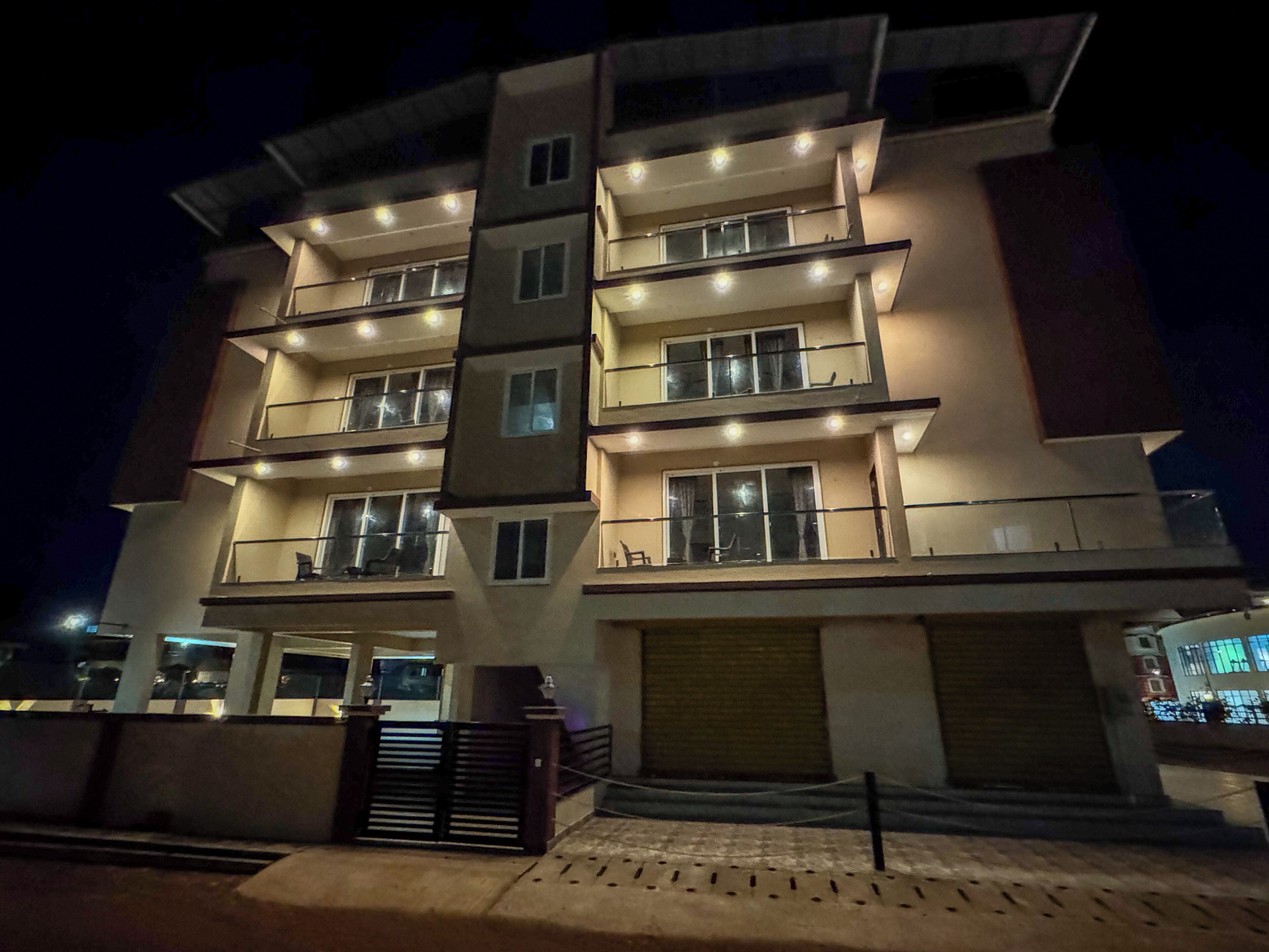 Un edificio residencial de varios pisos con balcones, ventanas amplias y una entrada con reja.