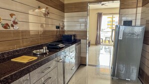 A modern kitchen with a marble countertop, stainless steel appliances, and wooden wall panels. - RK Homes Service Apartments (Vasco da Gama)