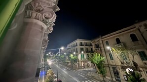 A nighttime street view with classical architecture, including ornate columns and a building with arched windows. - Epoque Room '1921' with Balcony (Messina)