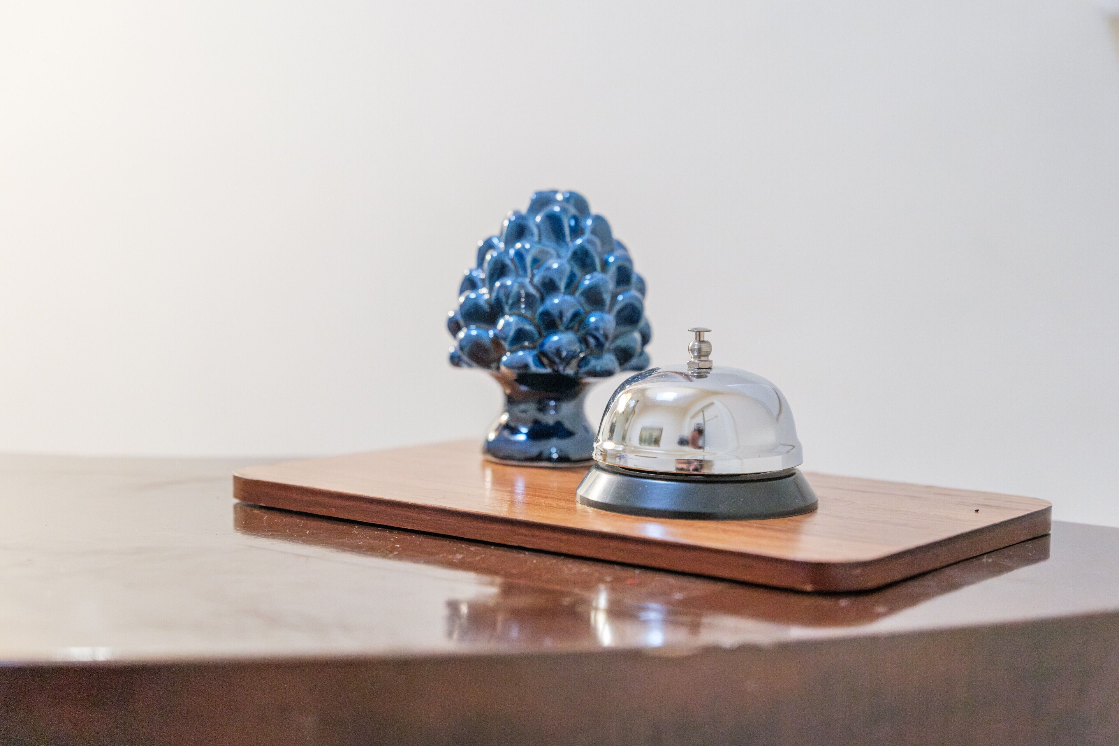 A wooden reception desk with a clear glass bell and a blue decorative object.
