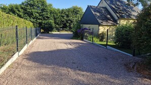 A gravel driveway leading to a house with a fenced yard and a chimney.