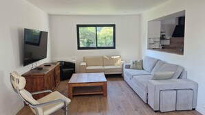 A living room with a TV, two sofas, a wooden coffee table, and a chair.