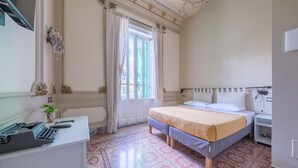 A bedroom with a bed, a desk with a typewriter, a radiator, and a window with curtains. - Epoque Room '1922' with Balcony (Messina)