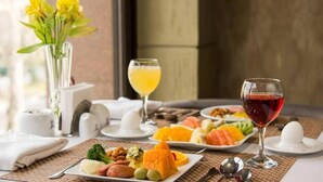 A breakfast setting with various dishes, a glass of red wine, and a glass of orange juice on a table.