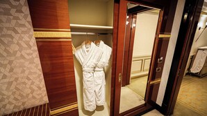 A wooden wardrobe with a mirror, a hanging robe, and a towel rack.