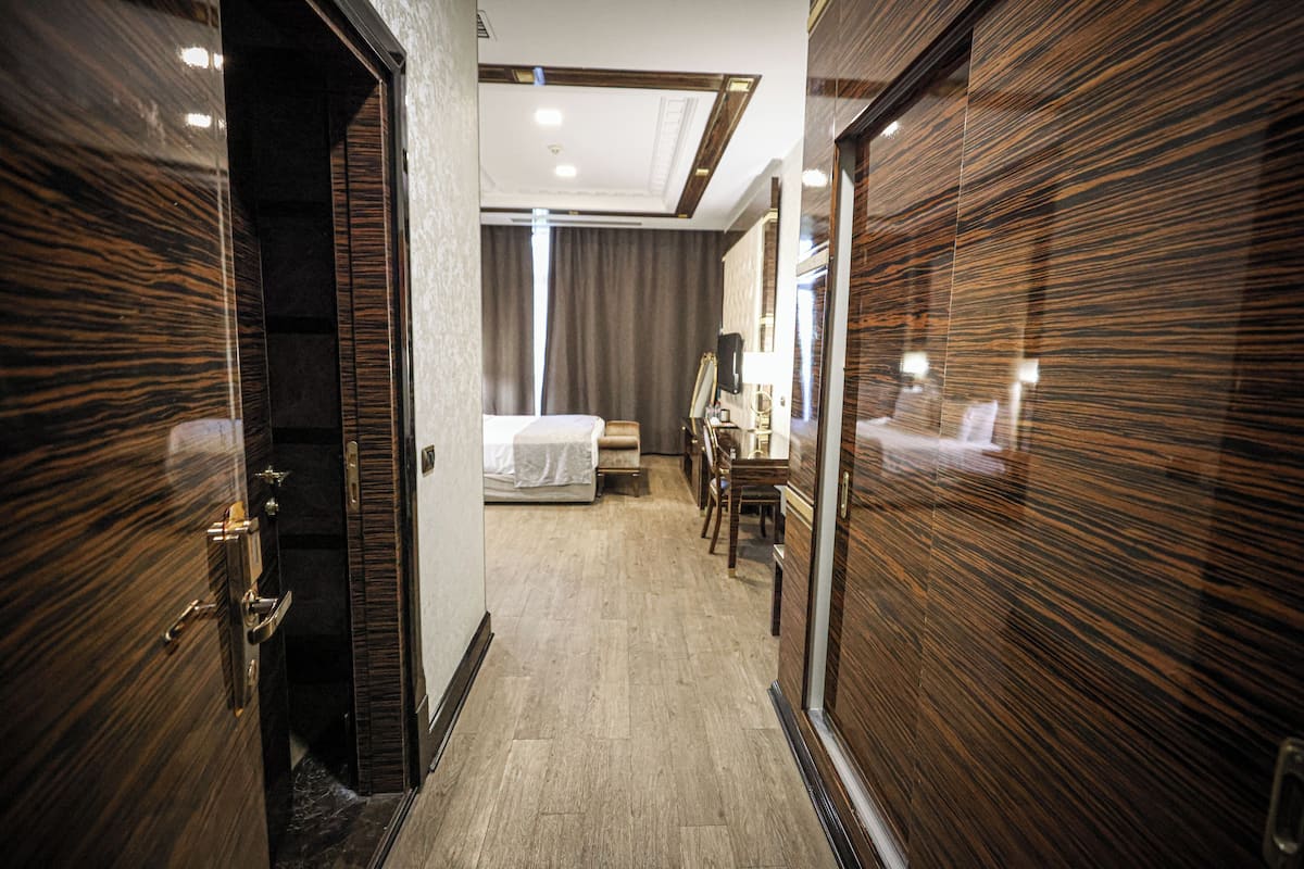 Een hotelkamer met een houten vloer, een bed, een bureau en een spiegel.