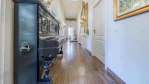 A hallway with a grand piano, a chandelier, and a large mirror. - Period Room '1923' with Balcony, Wi-Fi and Air Conditioning (Messina)
