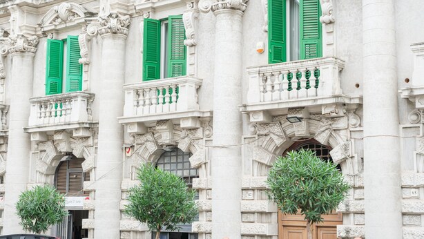 A classical building with ornate columns, green shutters, and a balcony with a railing. - Period Room '1925' with Wi-Fi and Air Conditioning (Messina)