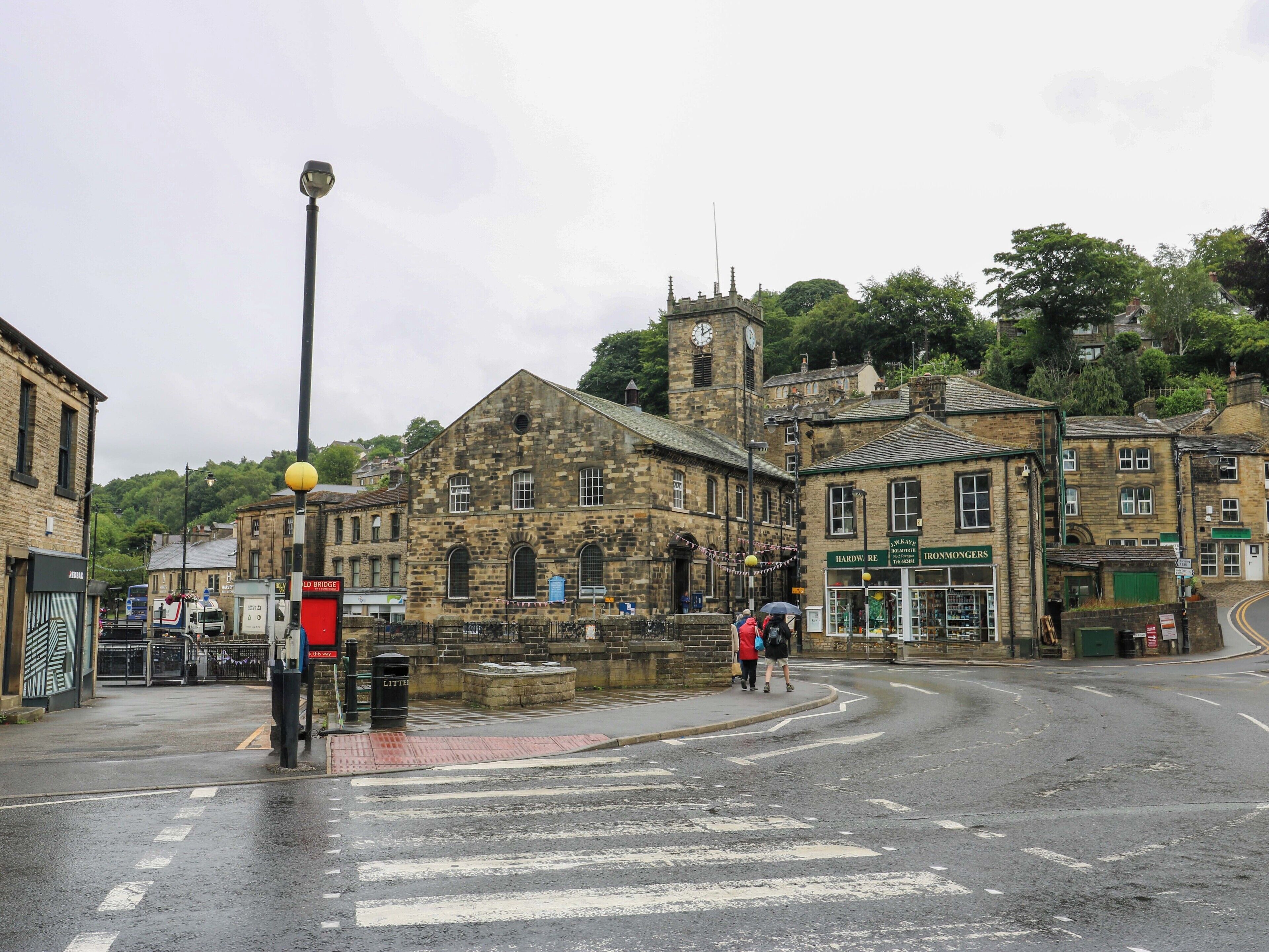 A historic stone building with a clock tower, a street with a pedestrian crossing, and a red traffic light.