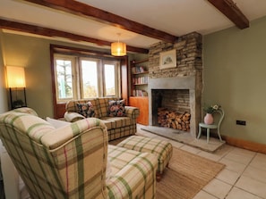 A cozy living room with a fireplace, plaid furniture, and a bookshelf. - Stone &amp; Fleece Cottage (Holmfirth)