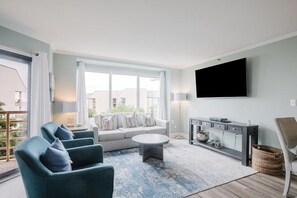 Un salon moderne comprenant un canapé, des fauteuils, une table basse, un téléviseur et une console.